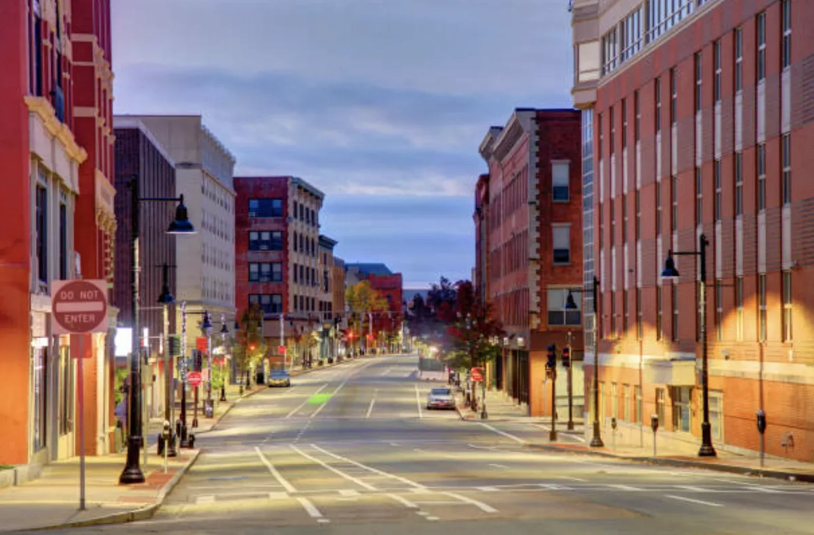 Downtown Brockton, Massachusetts at dusk, a quiet Main Street corridor lined with multi-story brick and stone commercial buildings